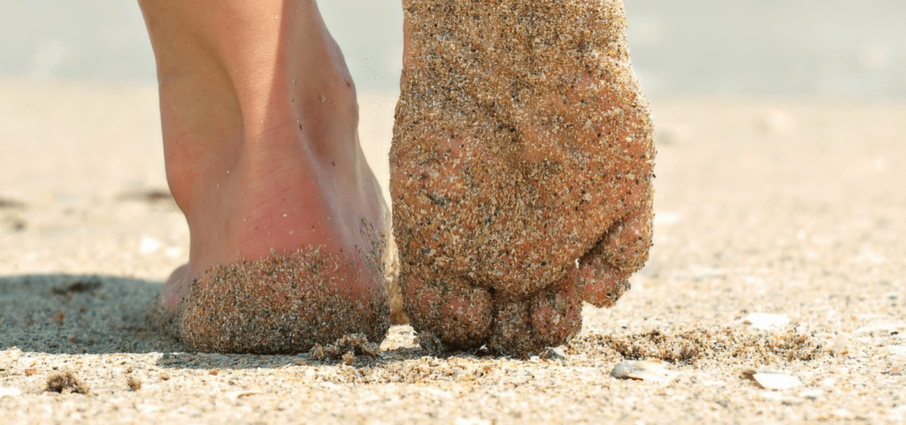Mit Sand bedeckte Füße am Strand - Fußplege